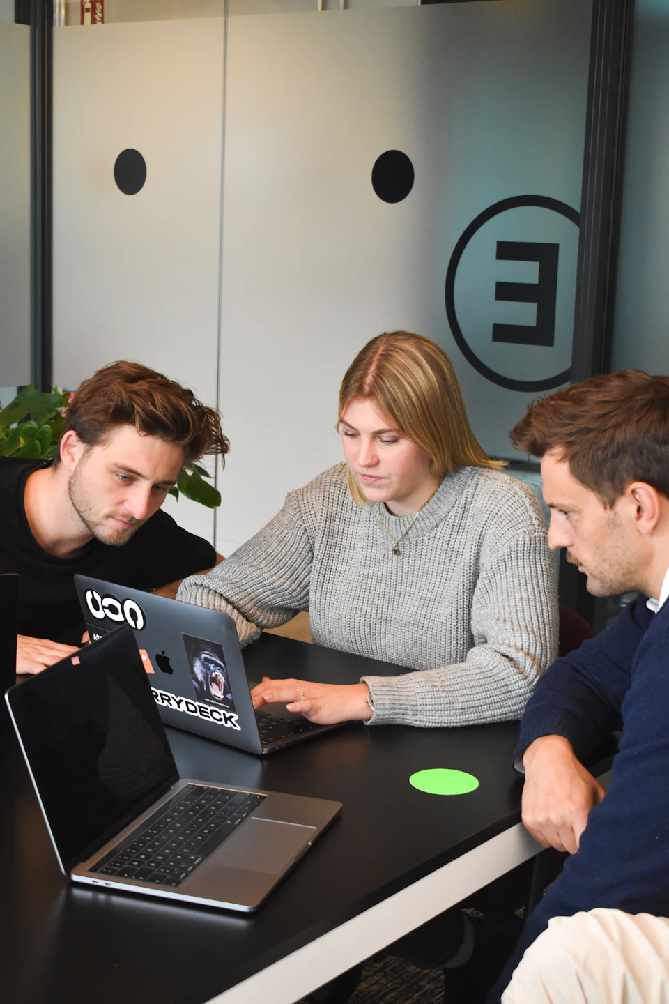 Three people reviewing work on a laptop